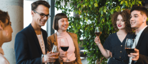 A group of four people enjoying a drink together in a modern office setting, smiling and chatting.